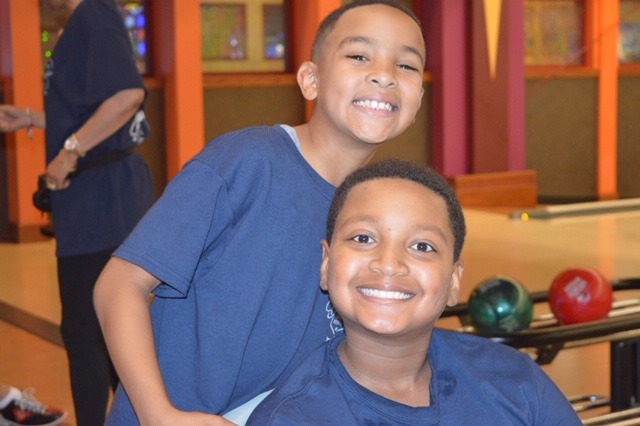 Two kids smiling by bowling ball return